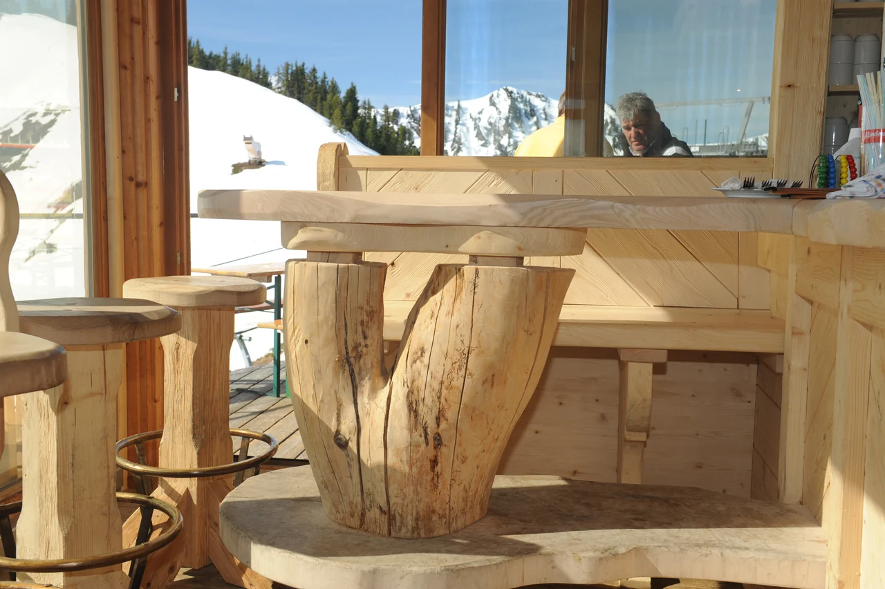 Innenraum auf der Riesneralm mit massiven Holztischen und Sitzmöbeln